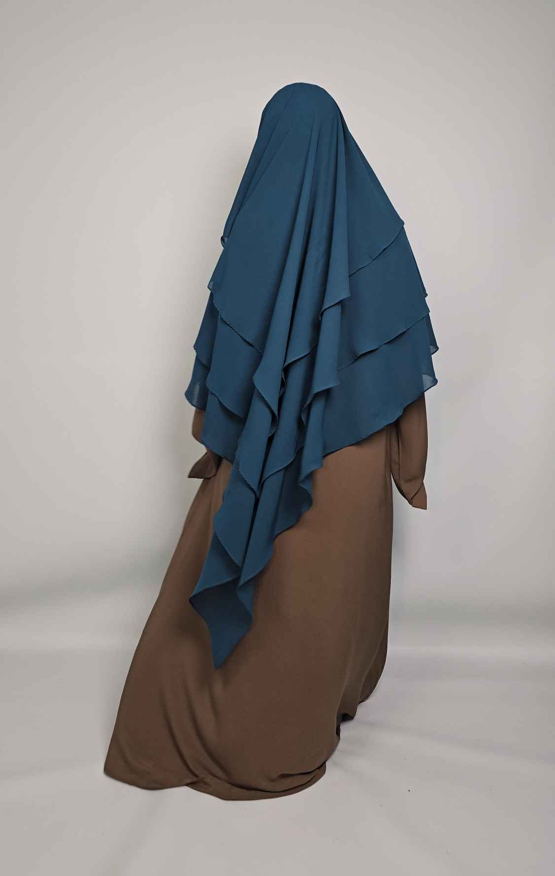 Back view of women wearing a brown abaya and a 3 layer khimar with niqab ties on a white background