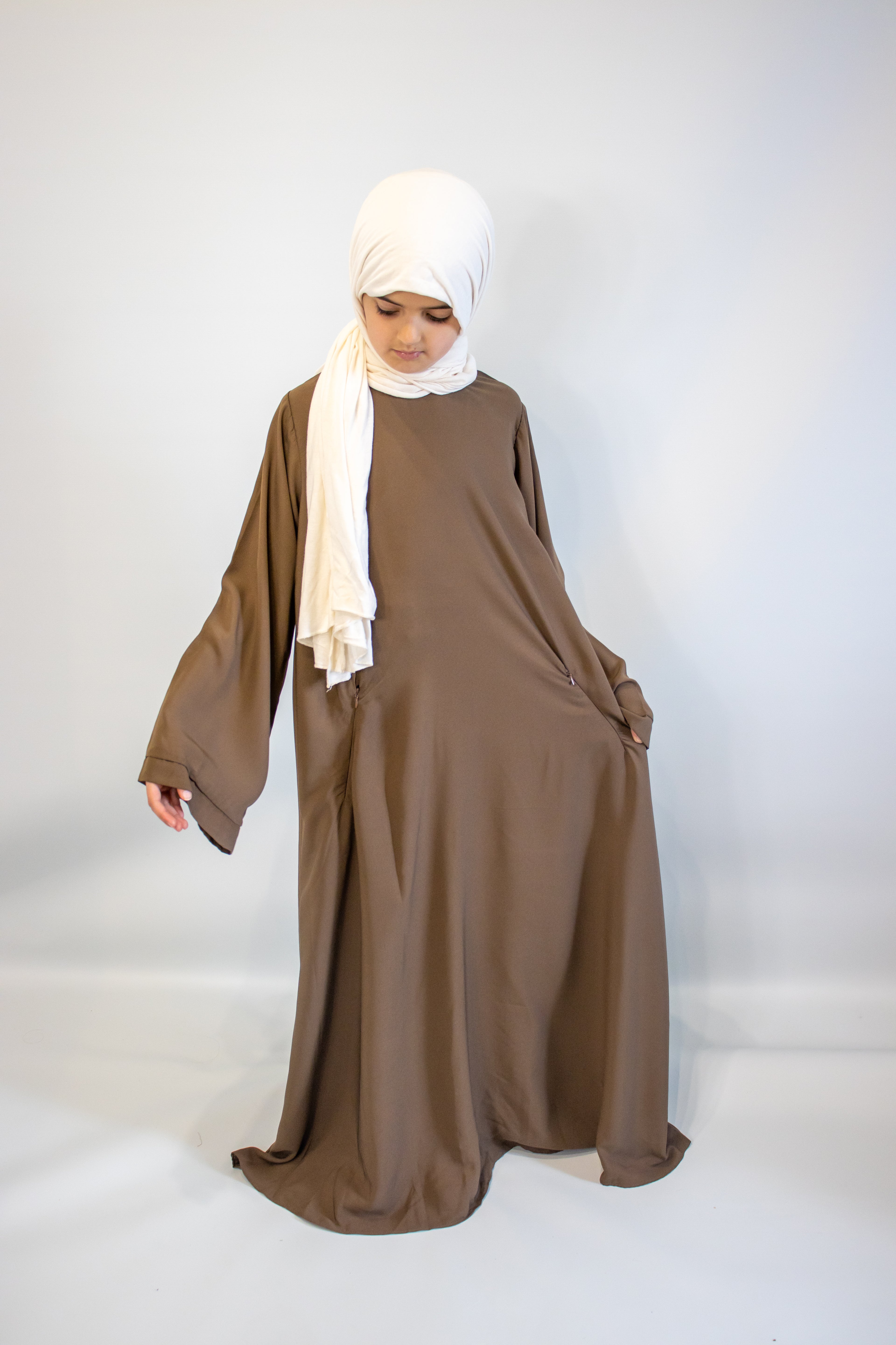 Woman wearing a brown dress and white hijab on a white background