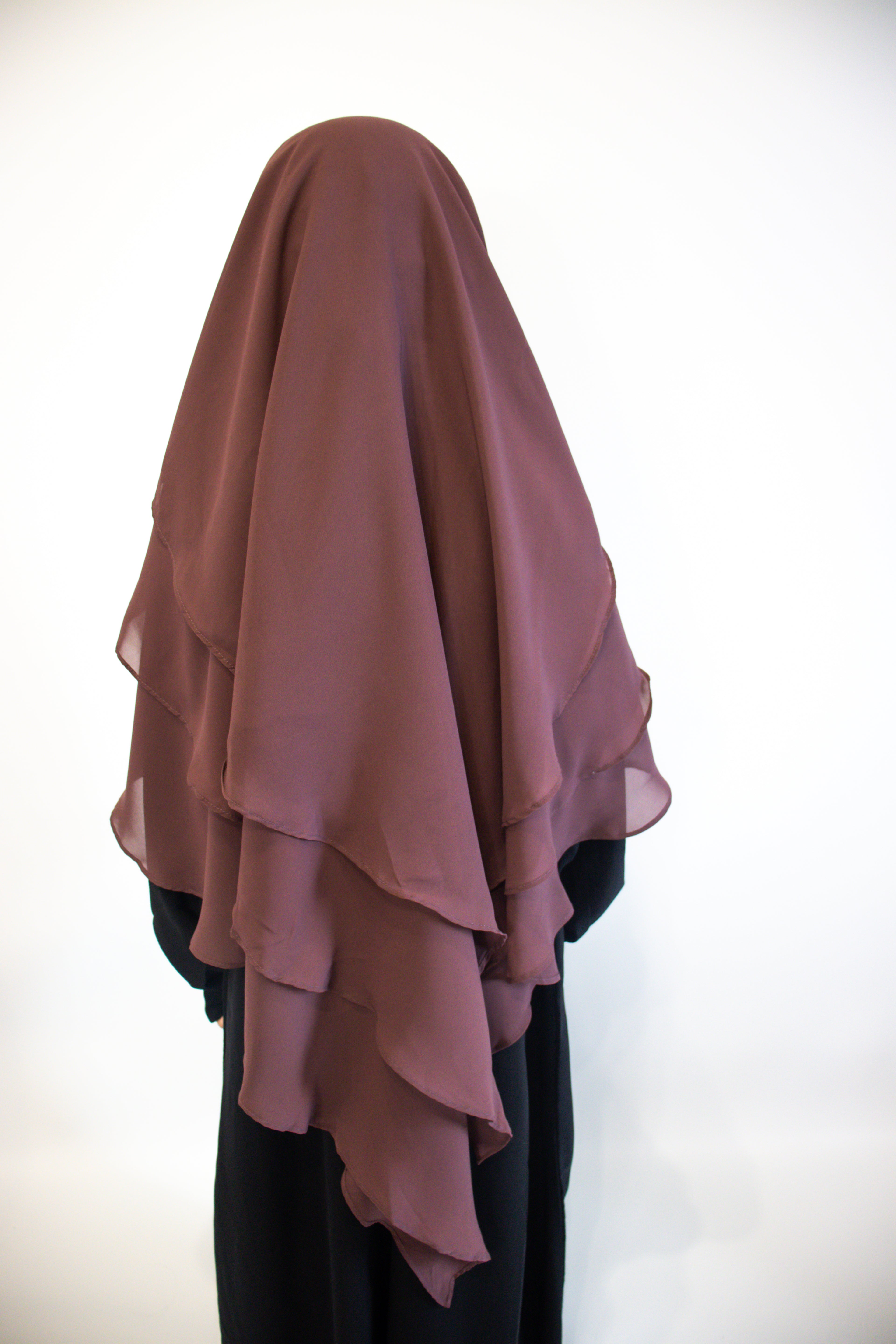 A Girl wearing a Mauve layered hijab against a white background