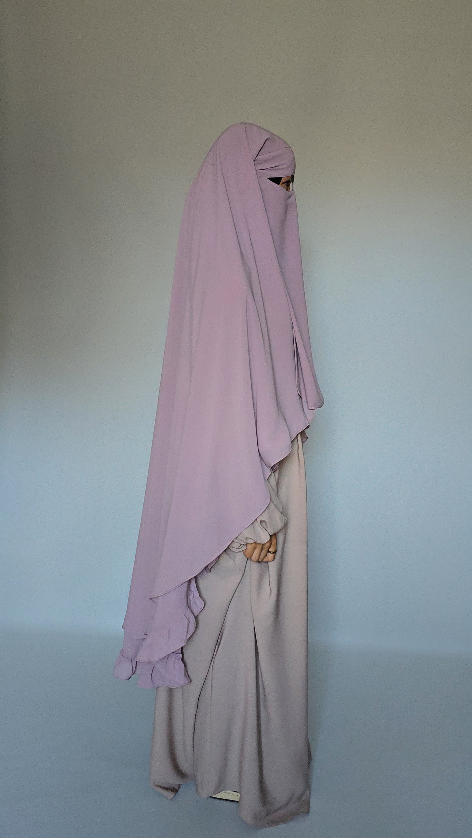 Wmen wear modest niqab garment with a cream abaya on a white studio background