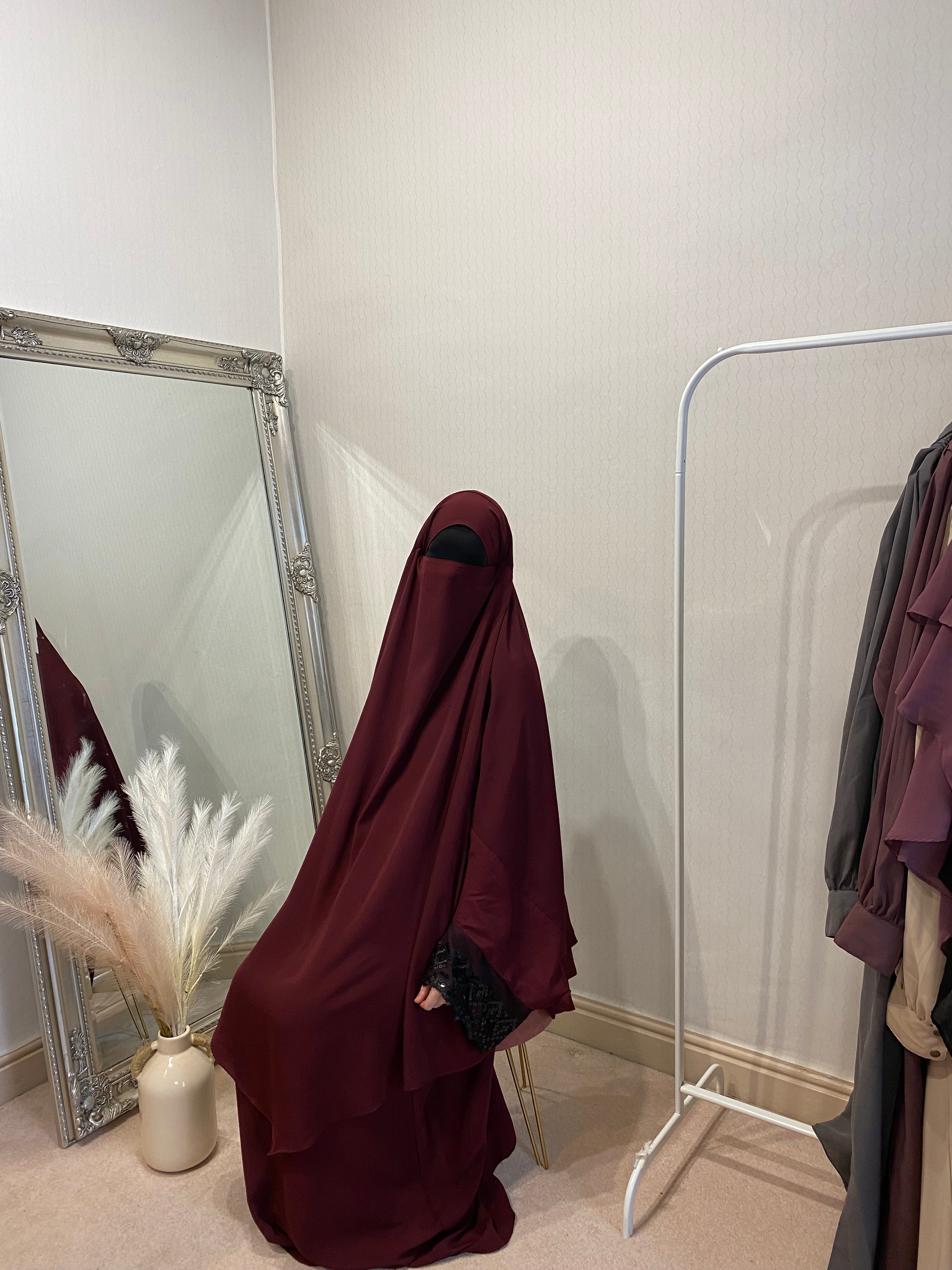 women sat in a two piece jilbab in a solid red colour with sequin wide sleeves