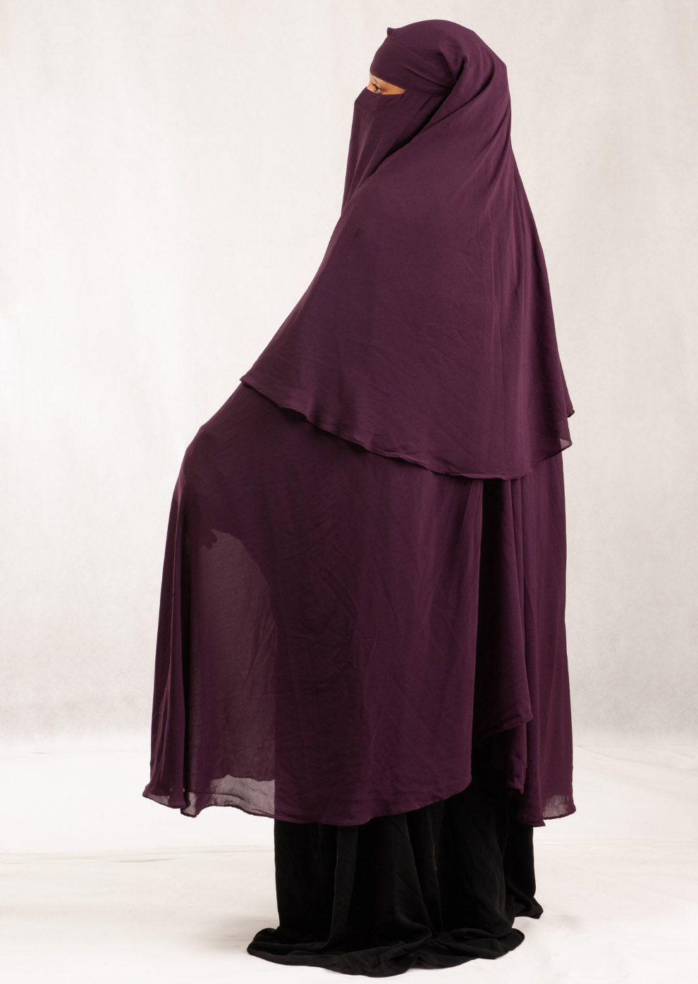 A woman wearing a purple extra long 3 layer niqab with buttons and a tieback headband.