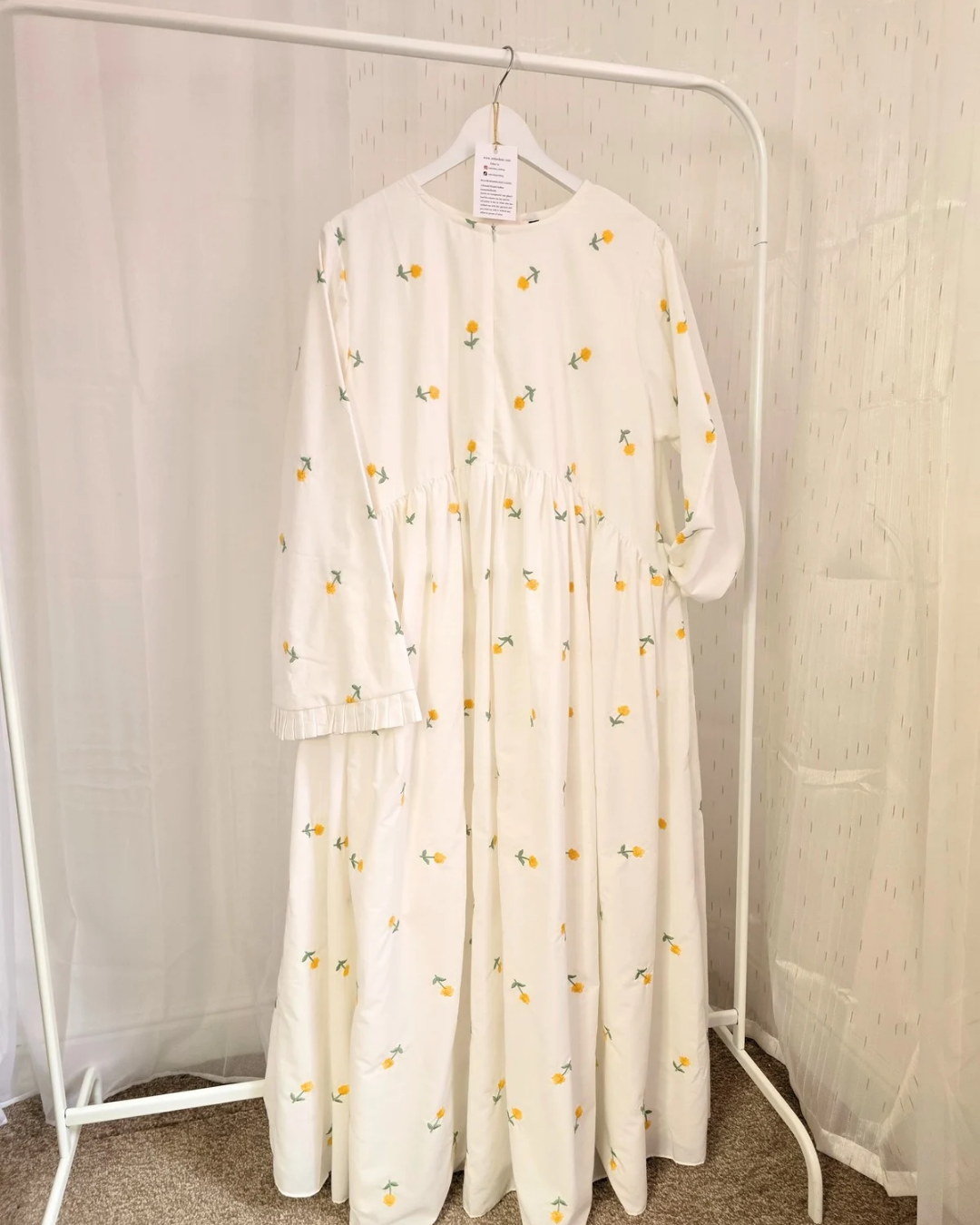 White dress with floral pattern on a hanger against a white background