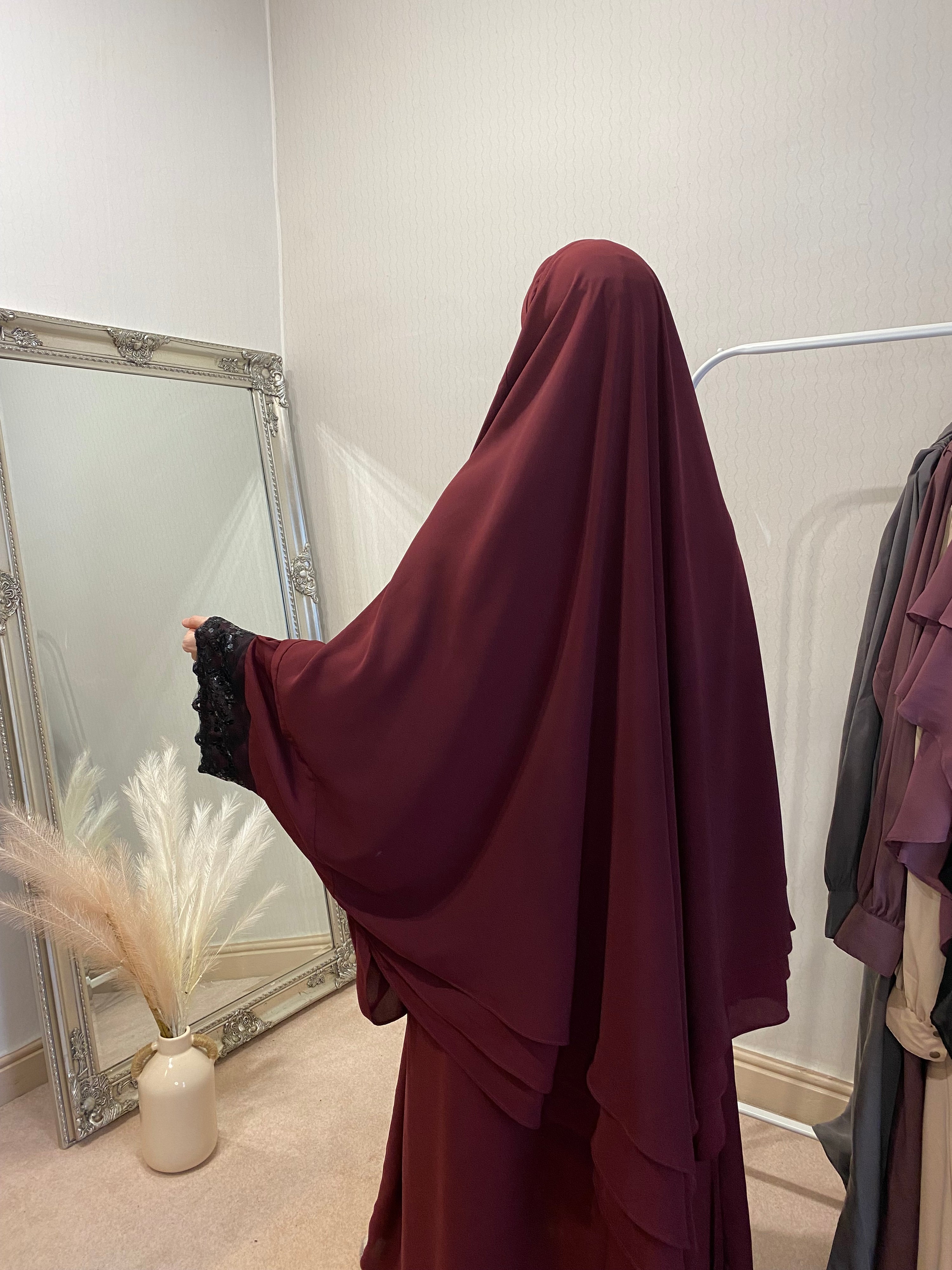 women looking in a mirror stood in a 3 layer solid red two piece jilbab with sequin wide sleeves