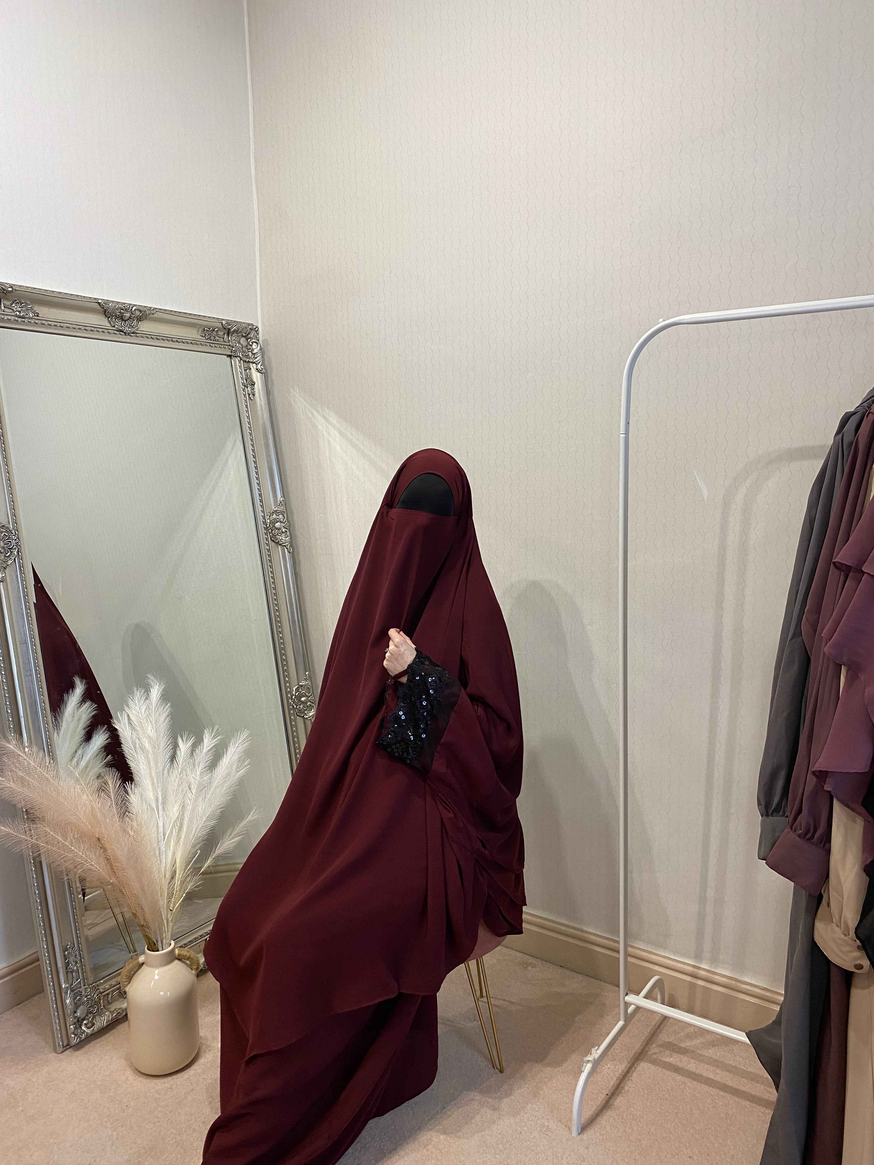 women sat in two piece solid red jilbab with a mirror behind her