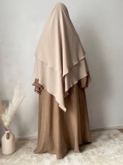 woman stood in a 2 layer cream khimar stood indoors 