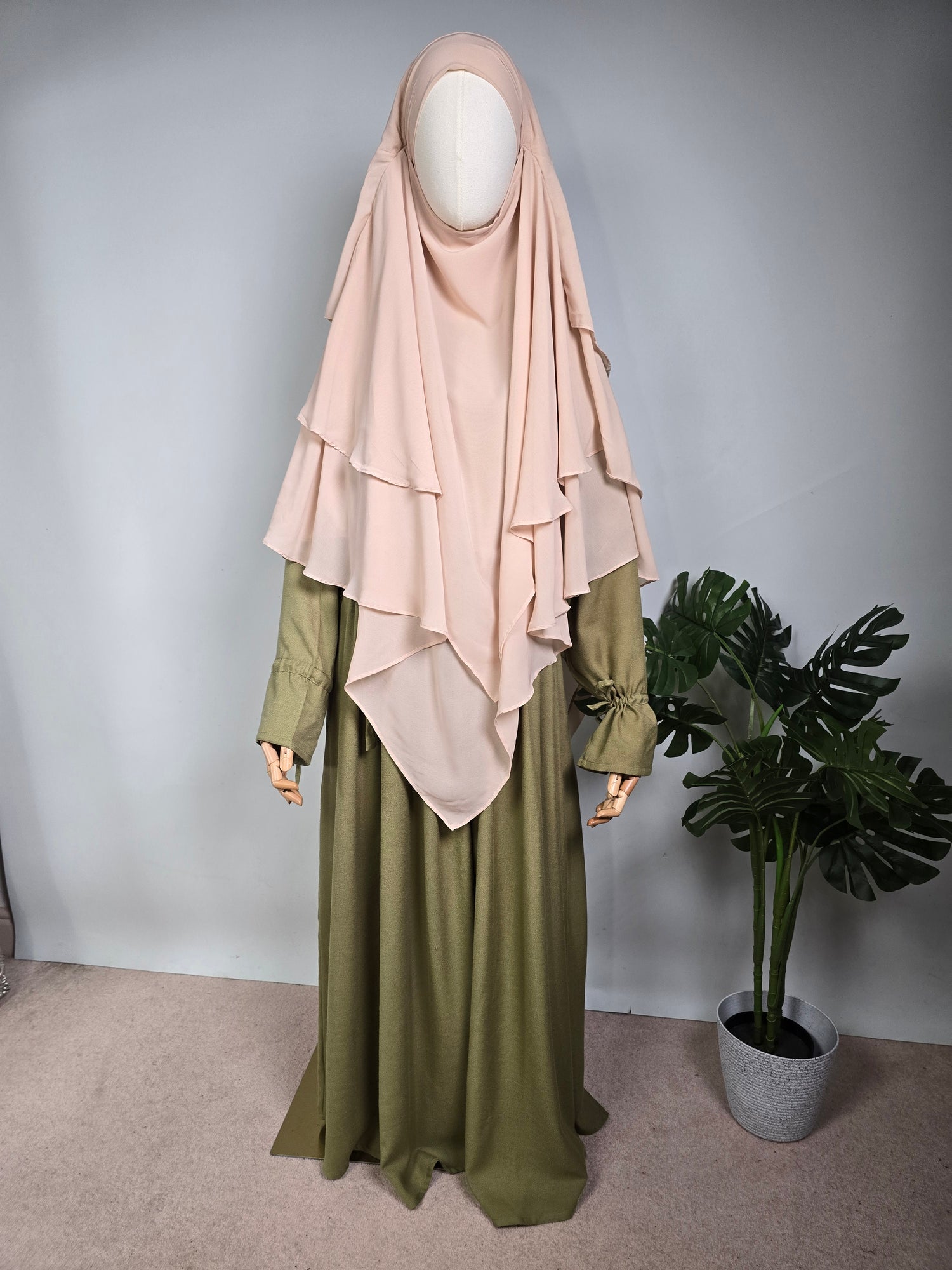 mannequin wearing a cream layered khimar with a sage green abaya on a white background 