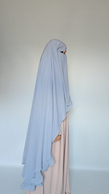 WOMEN WEAING A SKIES BLUE 3 LAYER GARMENT OVER HER HEAD COVERING HER BODY WITH A CREAM ABAYA AND ON A WHITE BACKGROUND 
