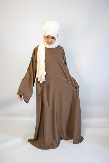 Woman wearing a brown dress and white hijab on a white background