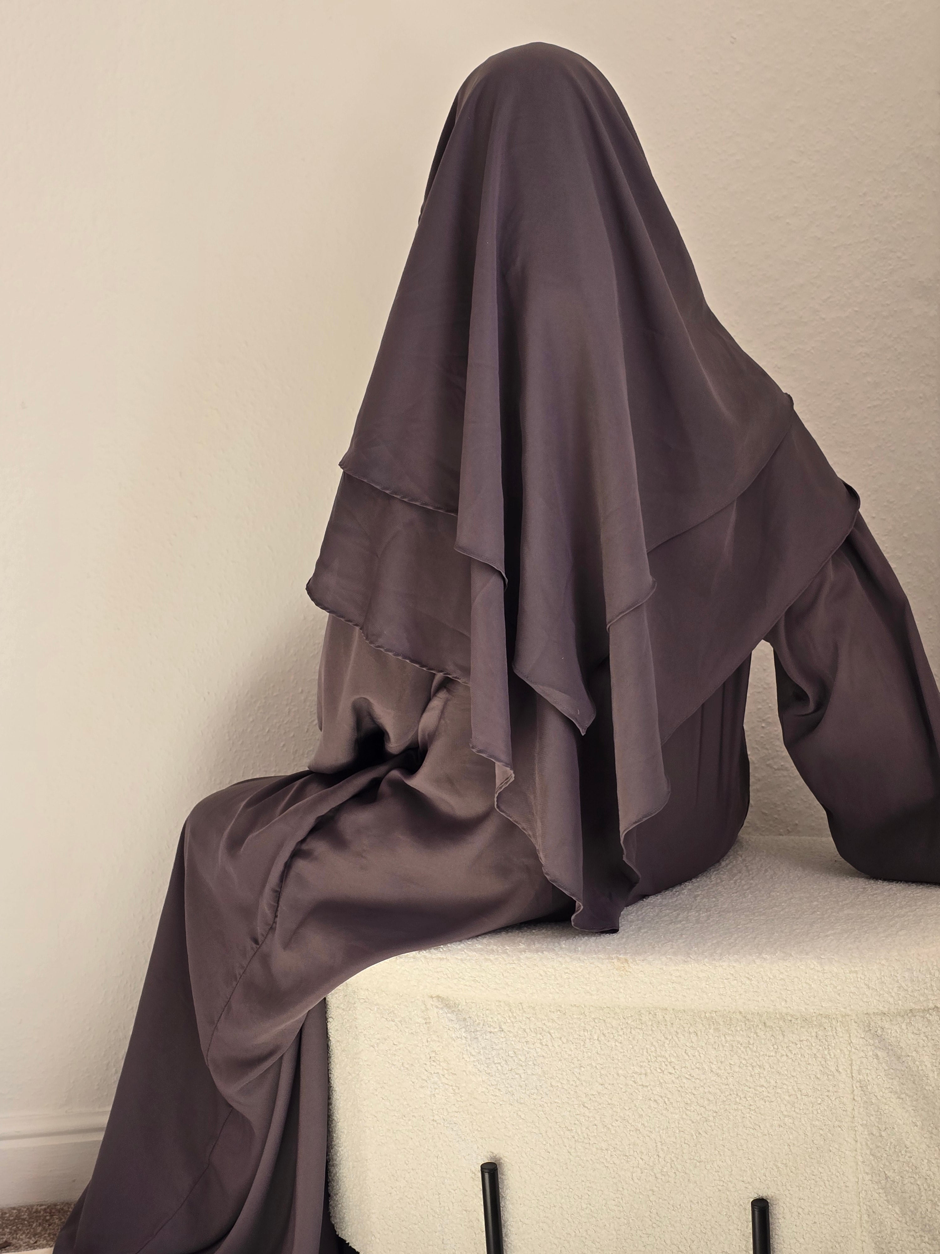 Women sat down modestly covered wearing a khimar and abaya set