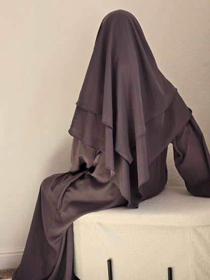 Women sat down modestly covered wearing a khimar and abaya set