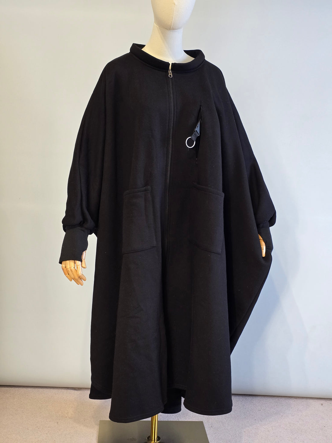 Black coat on a mannequin against a plain background