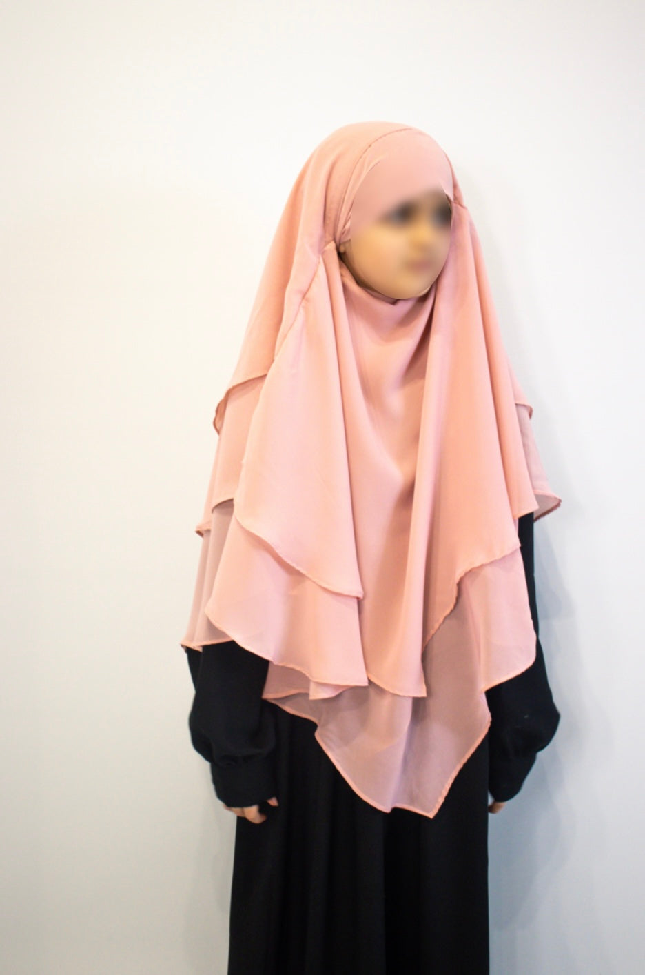 Person wearing a Baby pink hijab and black abaya against a white background