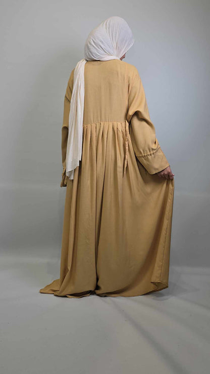 Person wearing a  long abaya with a white headscarf on a gray background