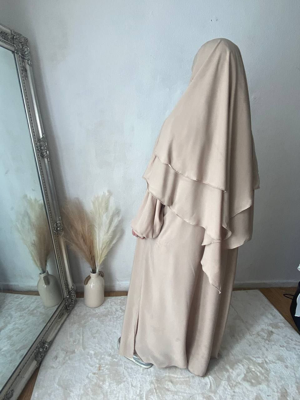 Cream abaya and khimar set on women stand facing a mirror