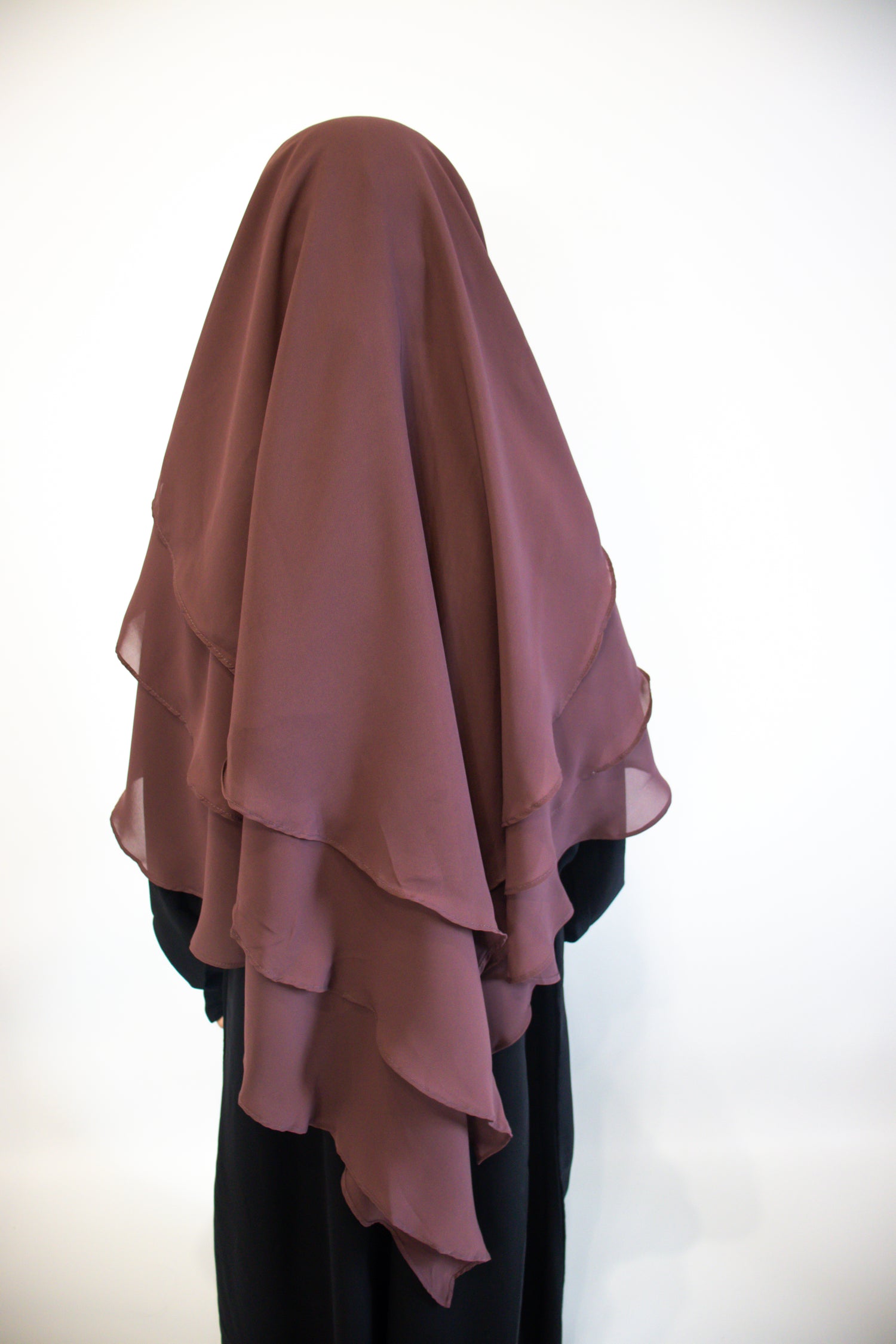 A Girl wearing a Mauve layered hijab against a white background