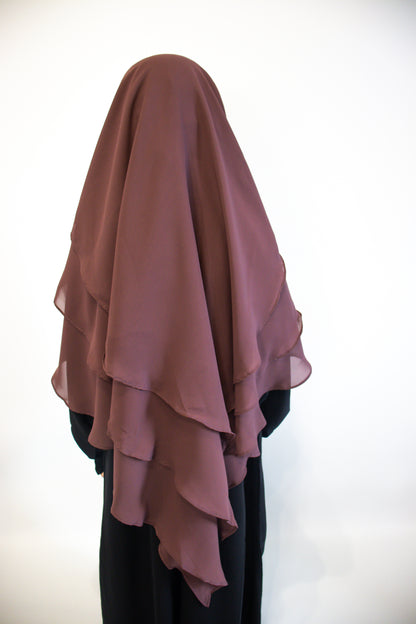 A Girl wearing a Mauve layered hijab against a white background