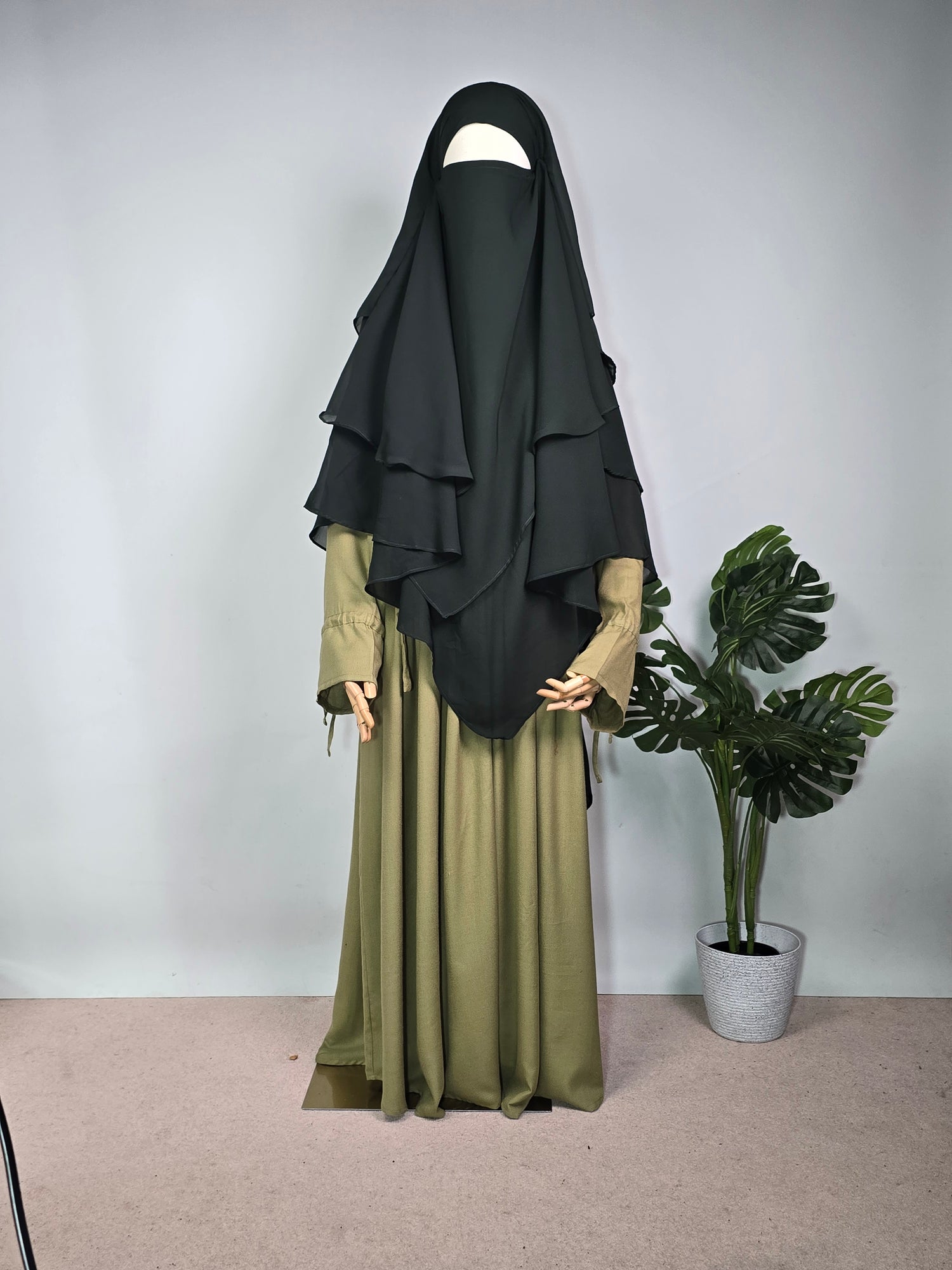 MANNEQUIN IN FOREST GREEN CHIFFON KHIMAR AND ABAYA DRESS ON A PLAN BACKGROUND