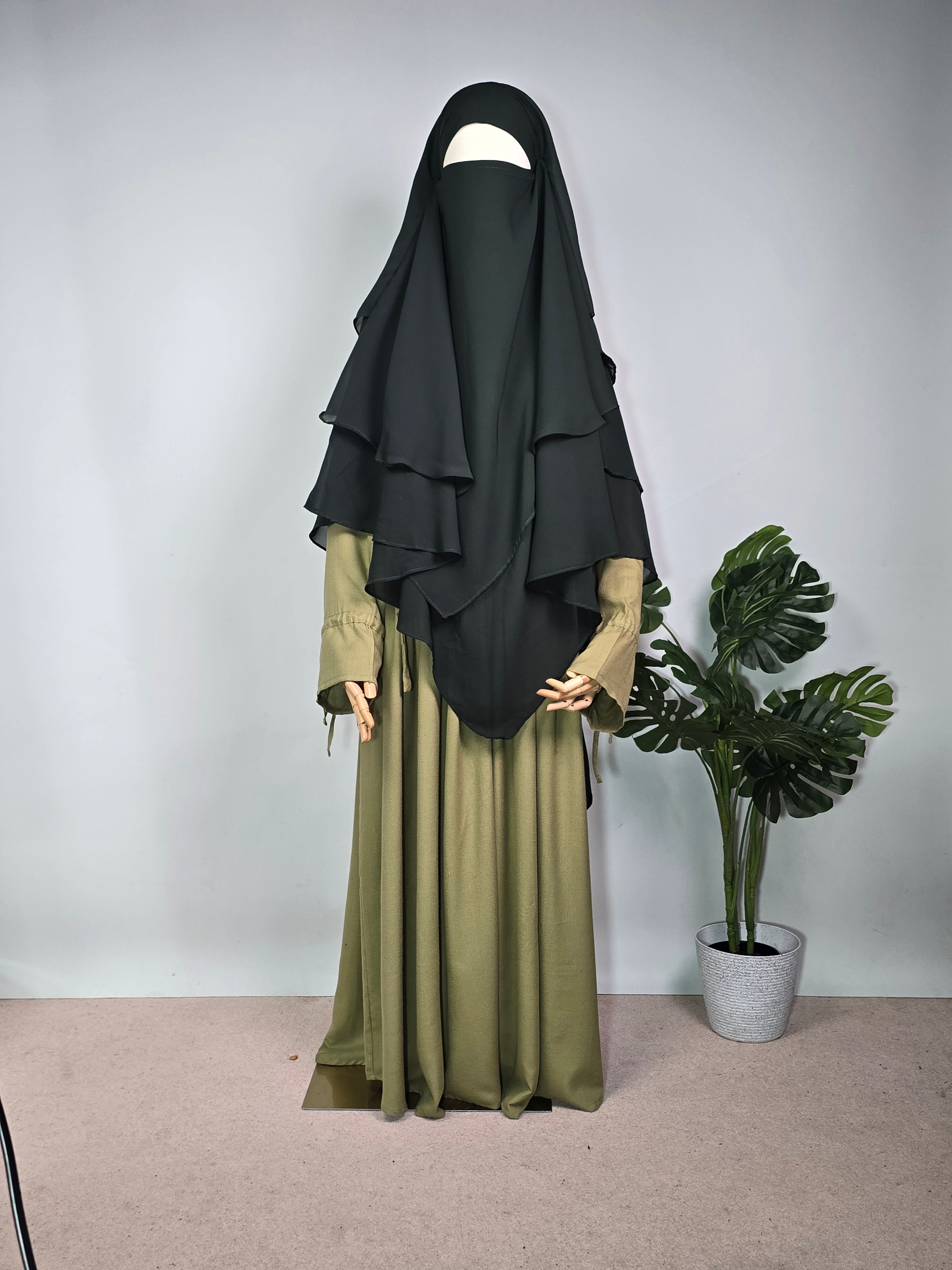 MANNEQUIN IN FOREST GREEN CHIFFON KHIMAR AND ABAYA DRESS ON A PLAN BACKGROUND