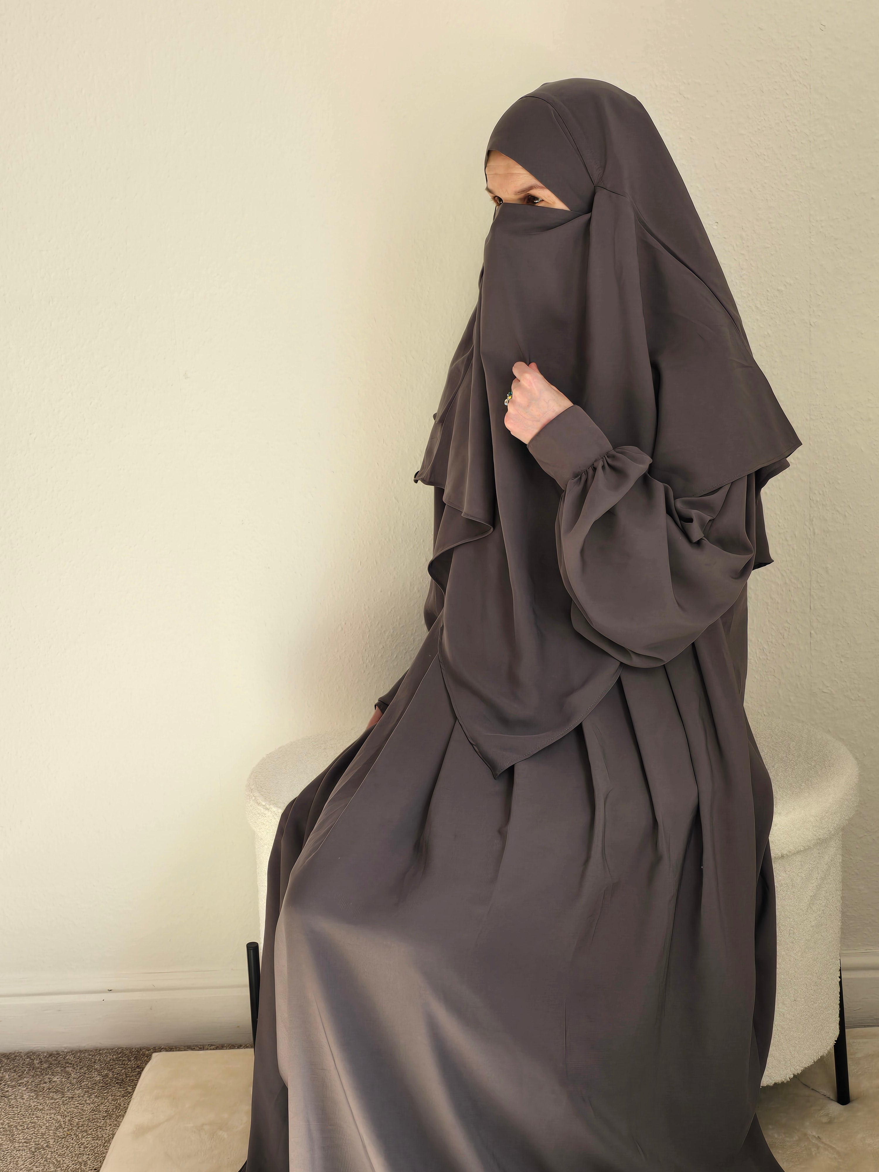 Women sit in a 2 piece abaya and khimar set 