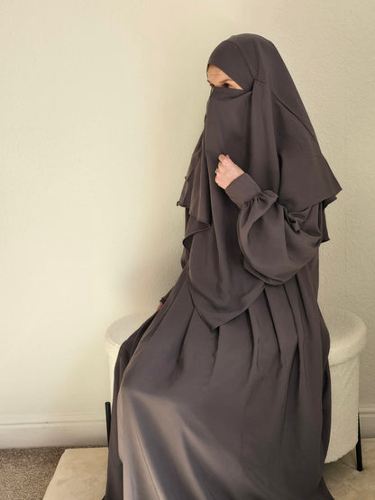Women sit in a 2 piece abaya and khimar set 