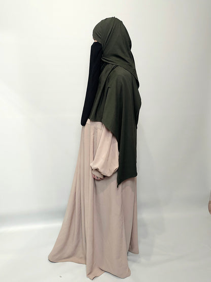 Person wearing a green hijab and beige dress on a white background