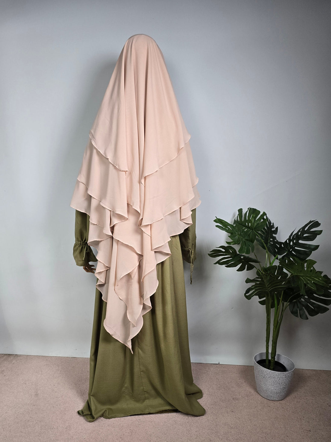 Mannequin wearing a perfect fitting Muslim women khimar paired with a sage green wide sleeve abaya on a white background