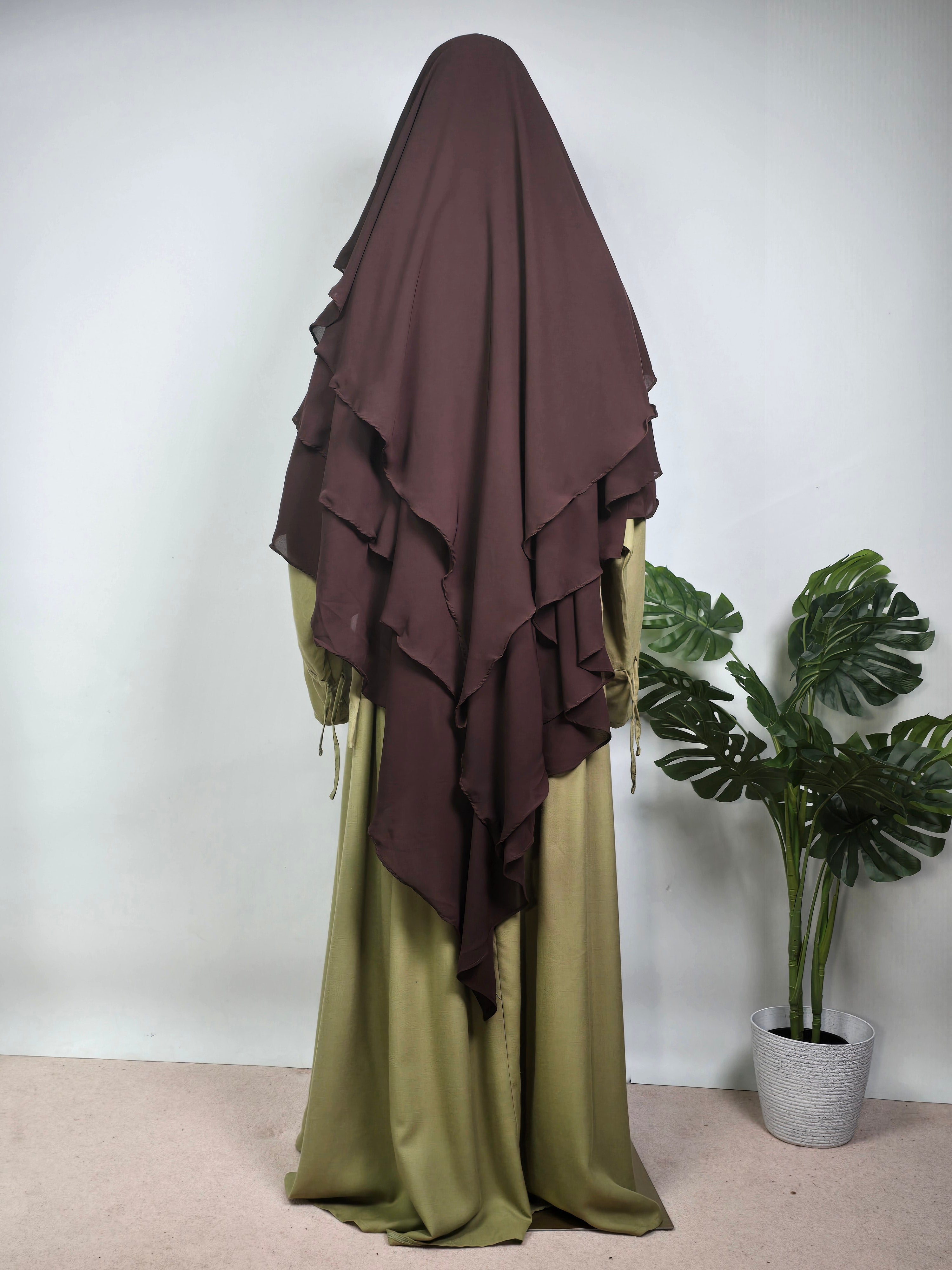mannequin wearing a dark brown 3 layer khimar with a sage green abaya on a white background 