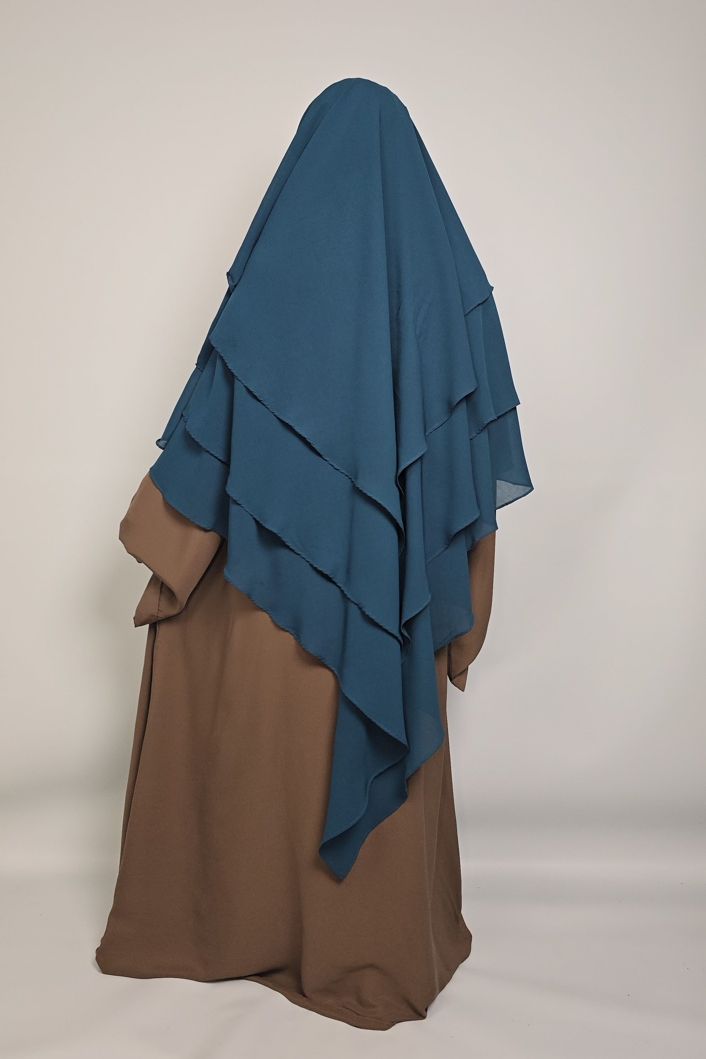 Women wearing a chiffon teal blue chiffon khimar with a brown abaya on a white background 