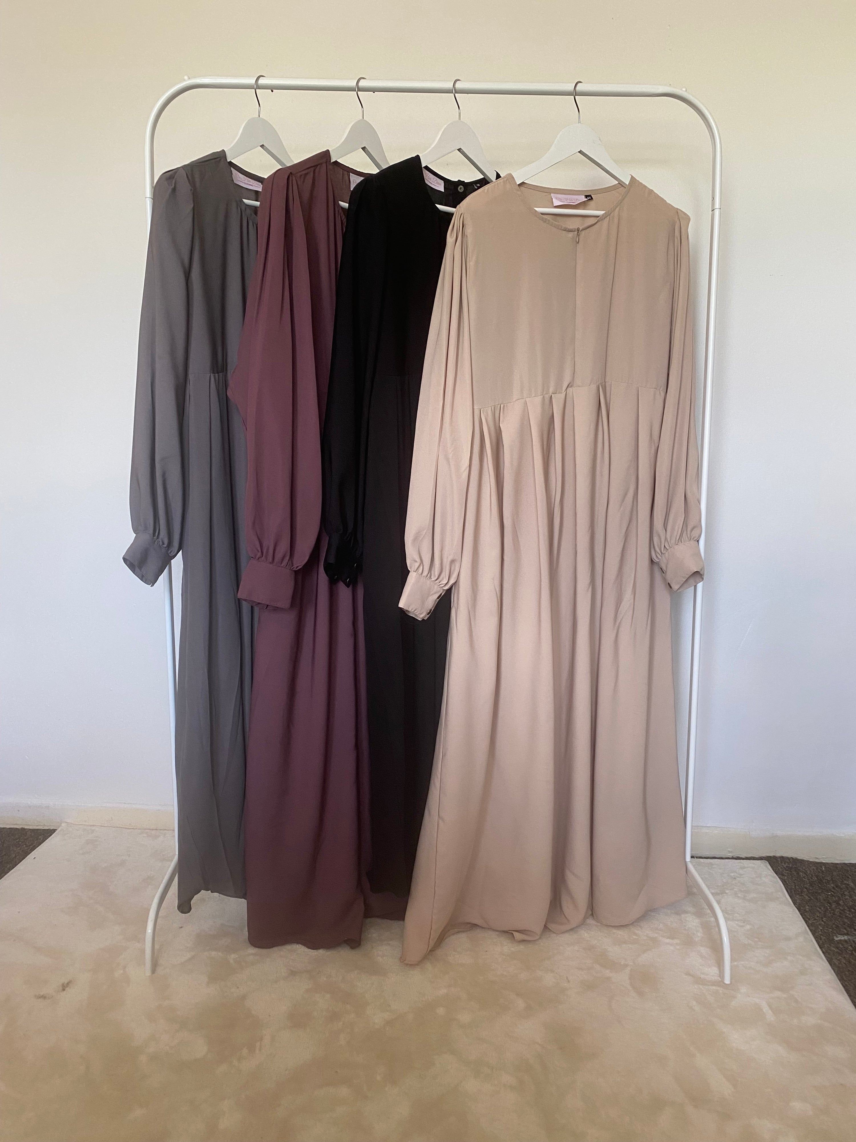 A mannequin displaying a black Russian abaya with long puffed sleeves, a high neckline, and a side pocket.