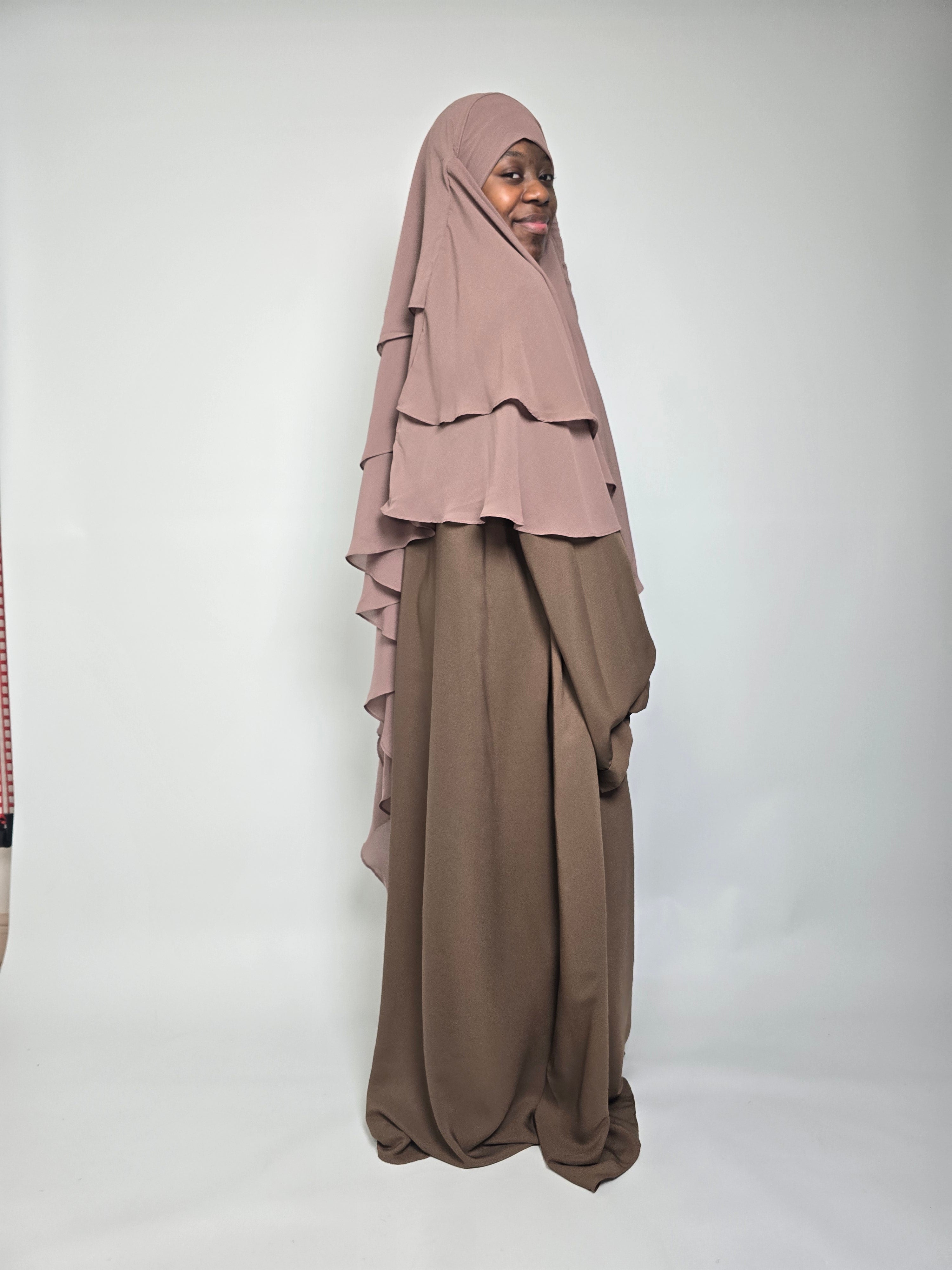 Brown abaya being  worn with a taupe brown khimar standing on a white surface