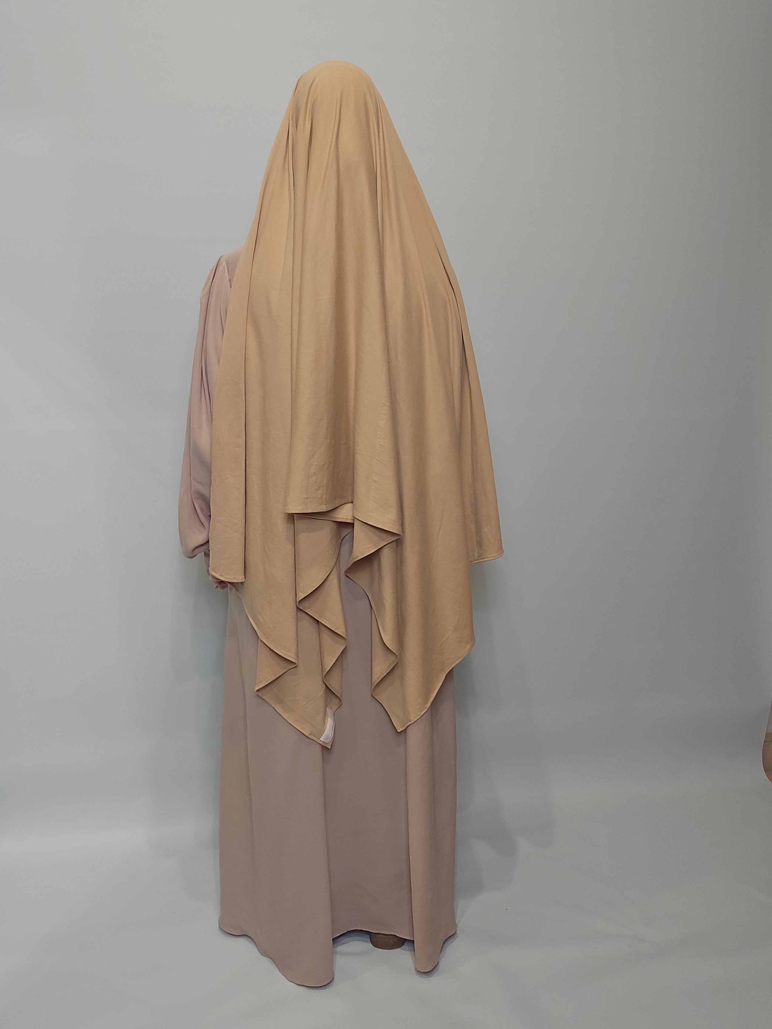 person in beige abaya with a maxi xl jersey hijab on a white background 

 