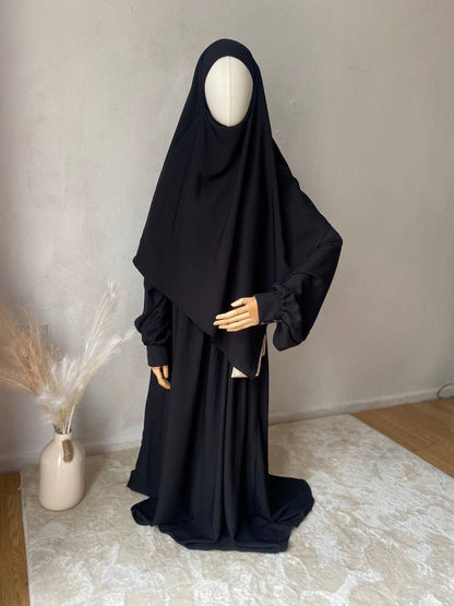 A mannequin displaying a black two-layer triangle khimar niqab with ties, designed for women&