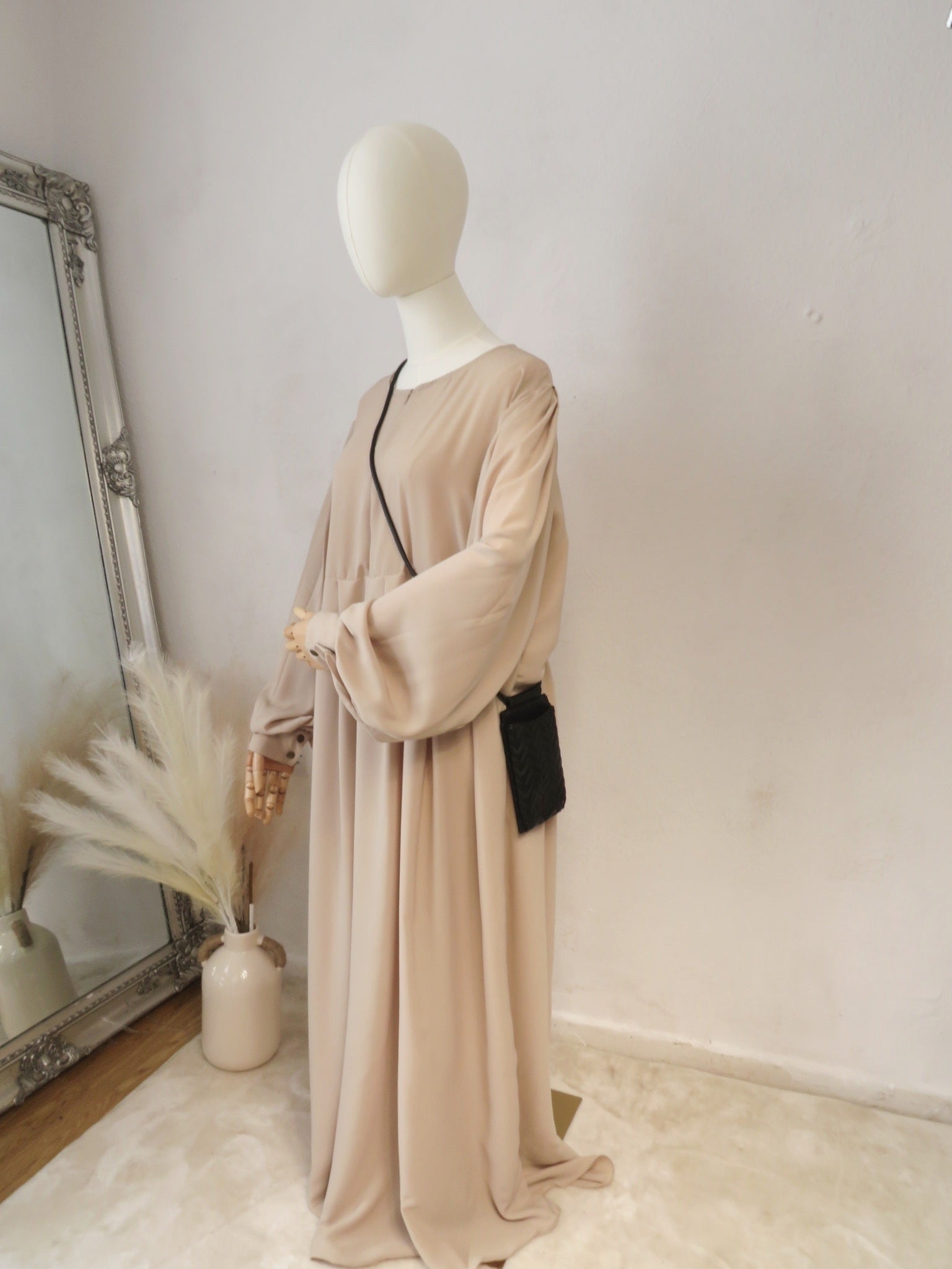 A mannequin displaying a Cream Russian abaya with long puffed sleeves, a high neckline, and a side pocket.