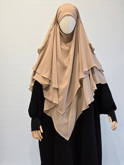 Beige 3 layer khimar with black coat with thumbhole  sleeves on a plain background