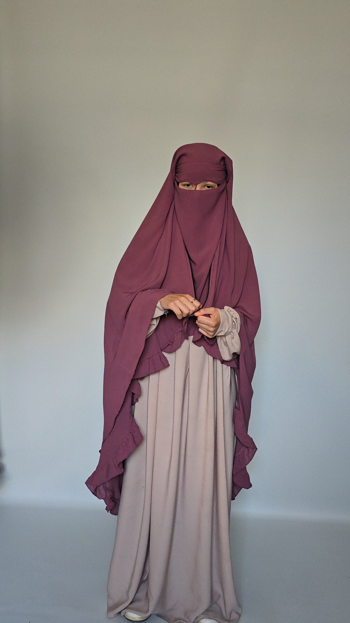 woman wearing 3 layer long modest niqab with widow peak style with a nose string on a white studio background 