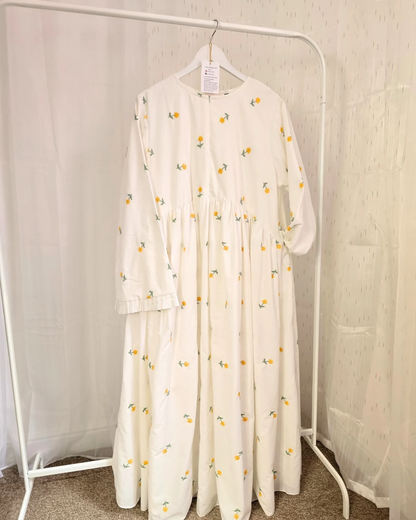 White dress with floral pattern on a hanger against a white background