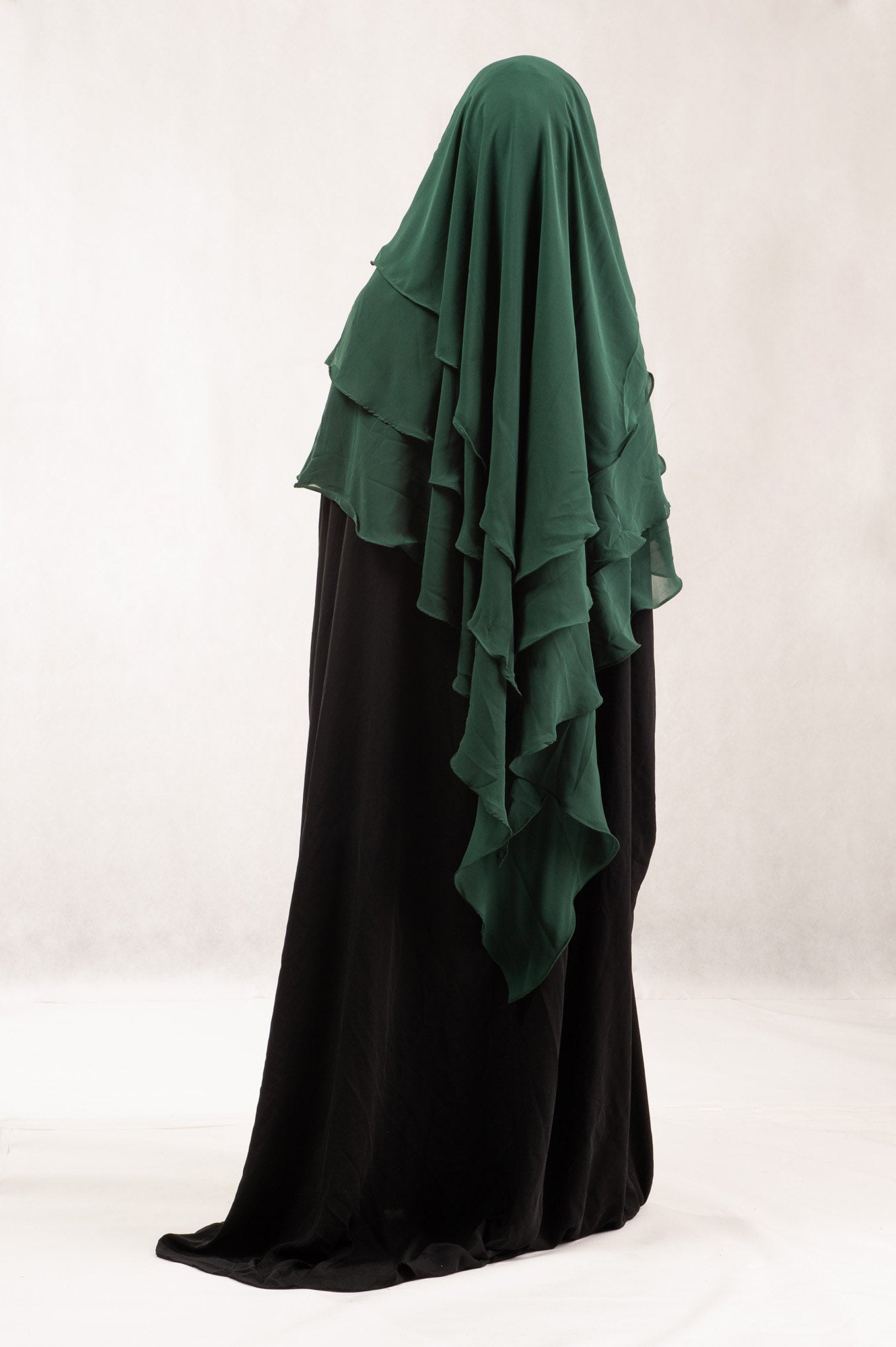 Green hijab draped over a black garment on a white background