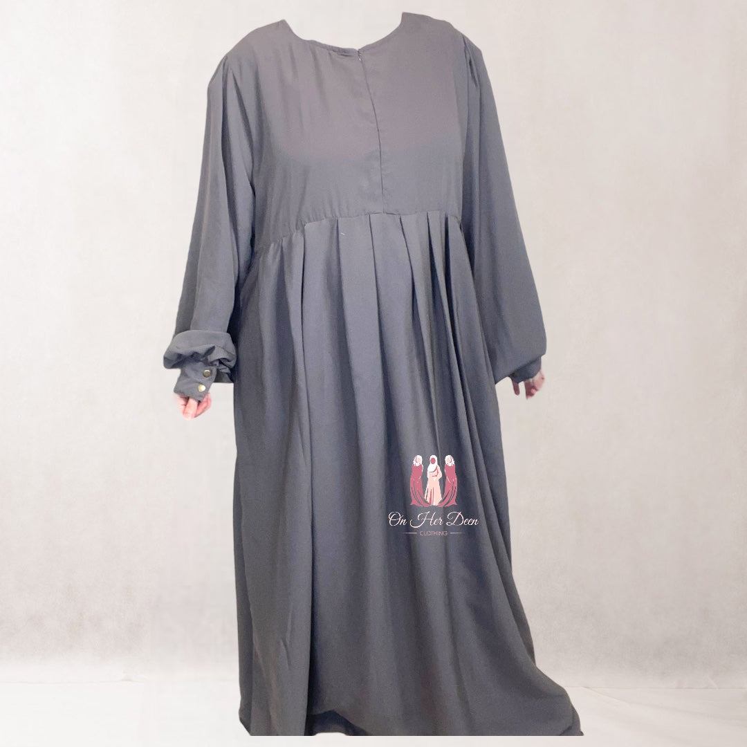 A mannequin displaying a grey  abaya with long puffed sleeves, a high neckline, and a side pocket.