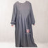 A mannequin displaying a grey  abaya with long puffed sleeves, a high neckline, and a side pocket.