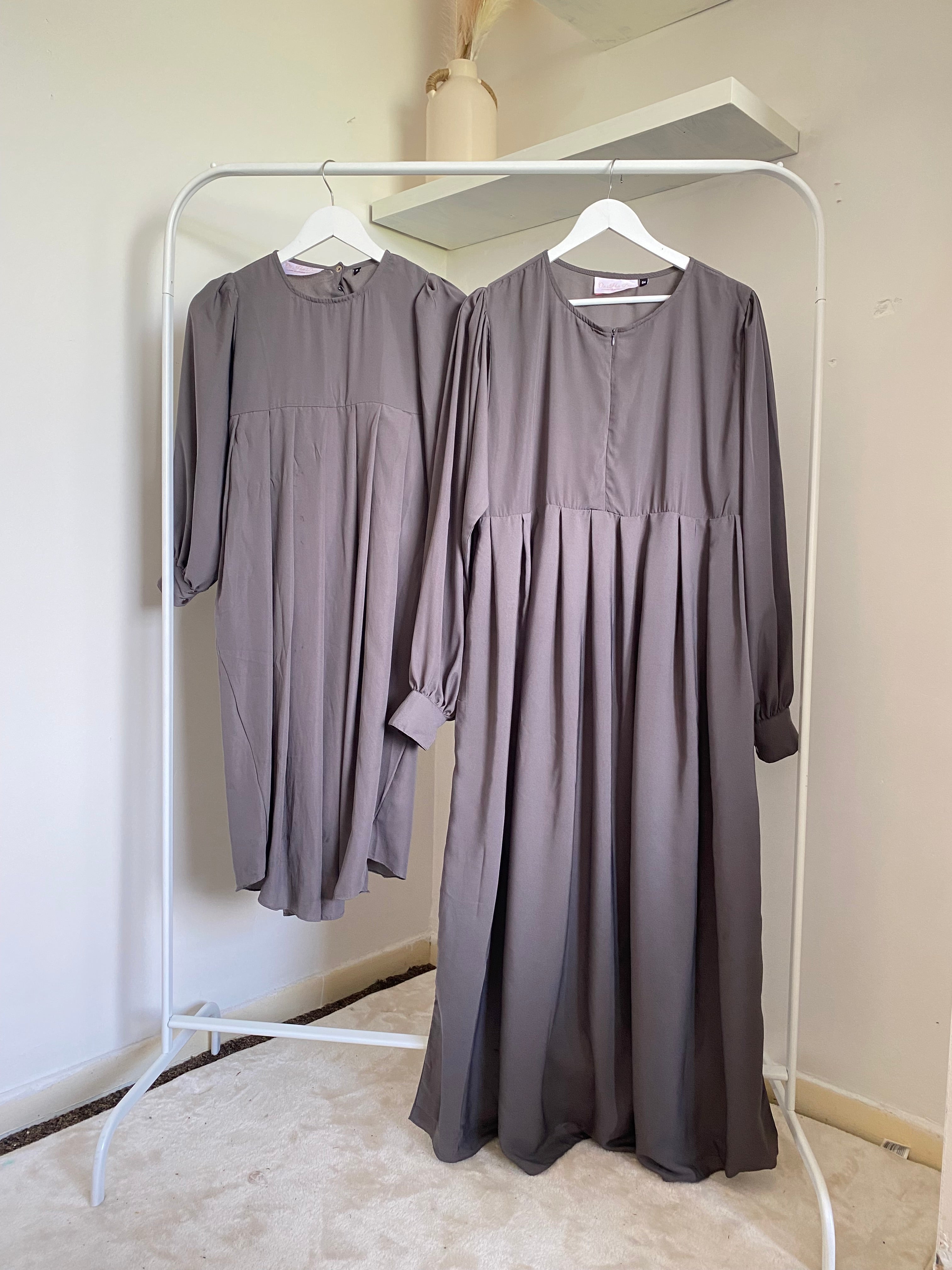 grey khimar and abaya hanging on a rail together 
