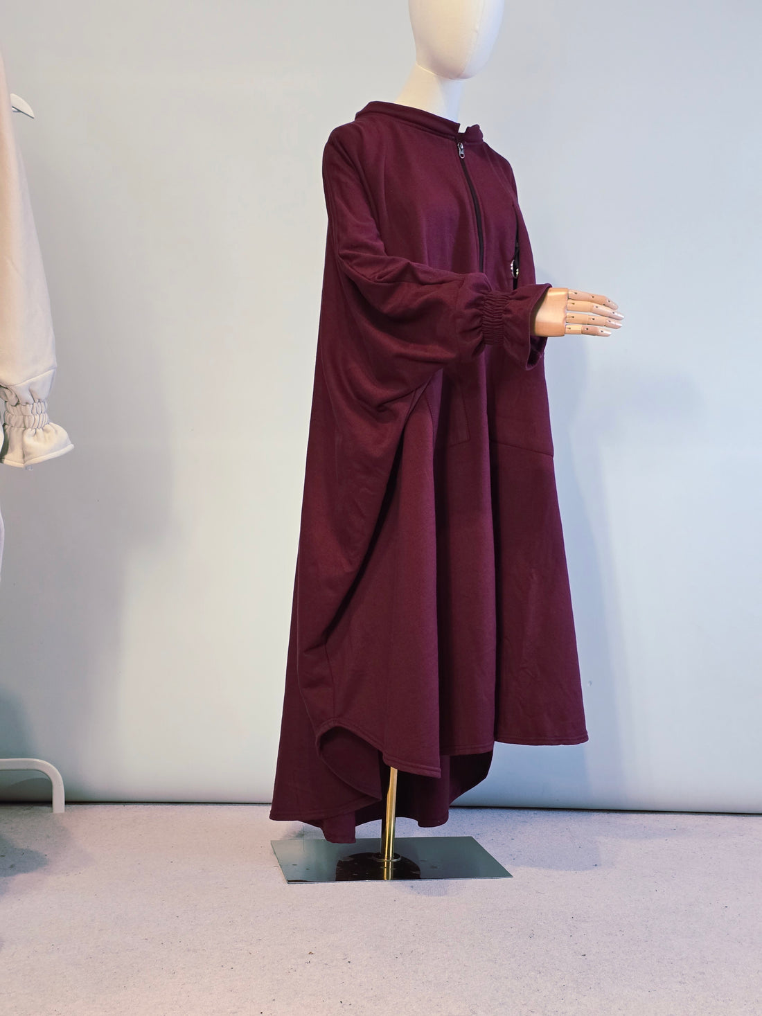 Maroon coat on a mannequin against a light gray wall