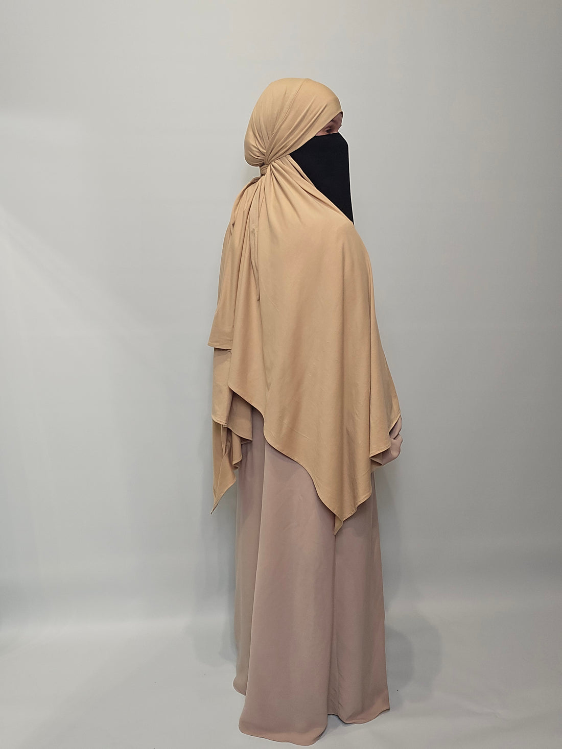 Beige abaya with matching hijab on a plain background
