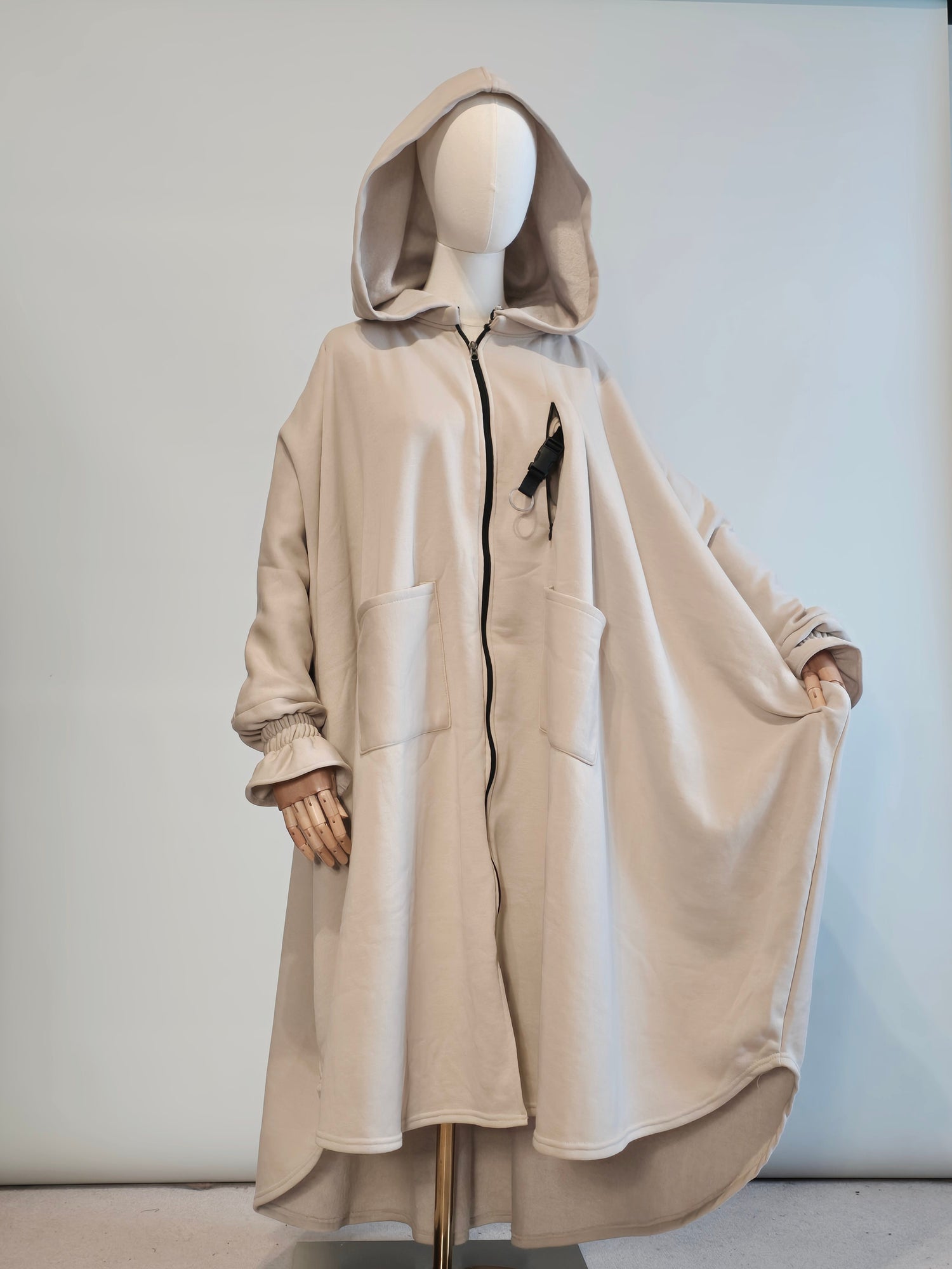 musk white hooded poncho abaya coat on a mannequin against a plain background