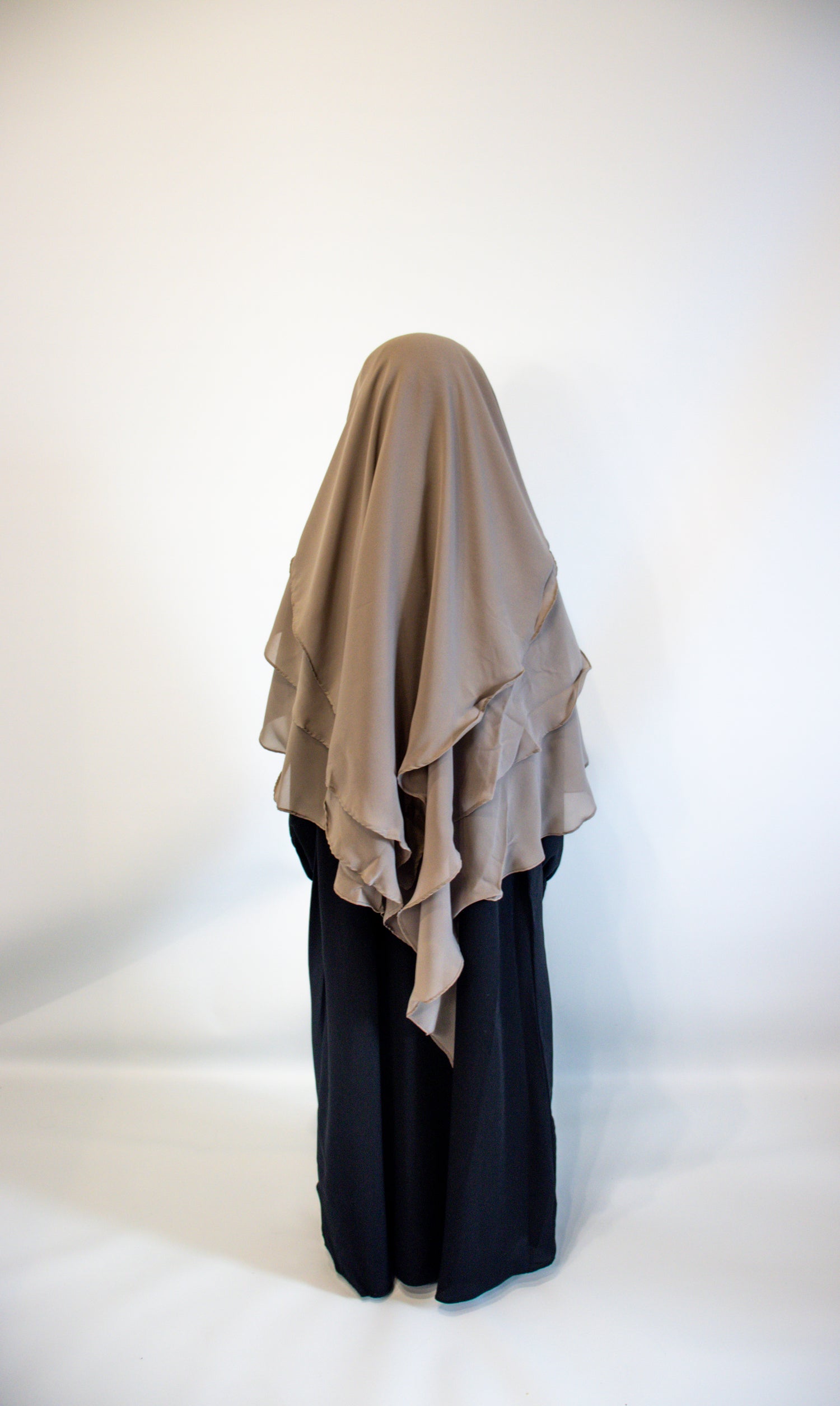 Girl wearing a Taupe grey hijab and black outfit on a white background