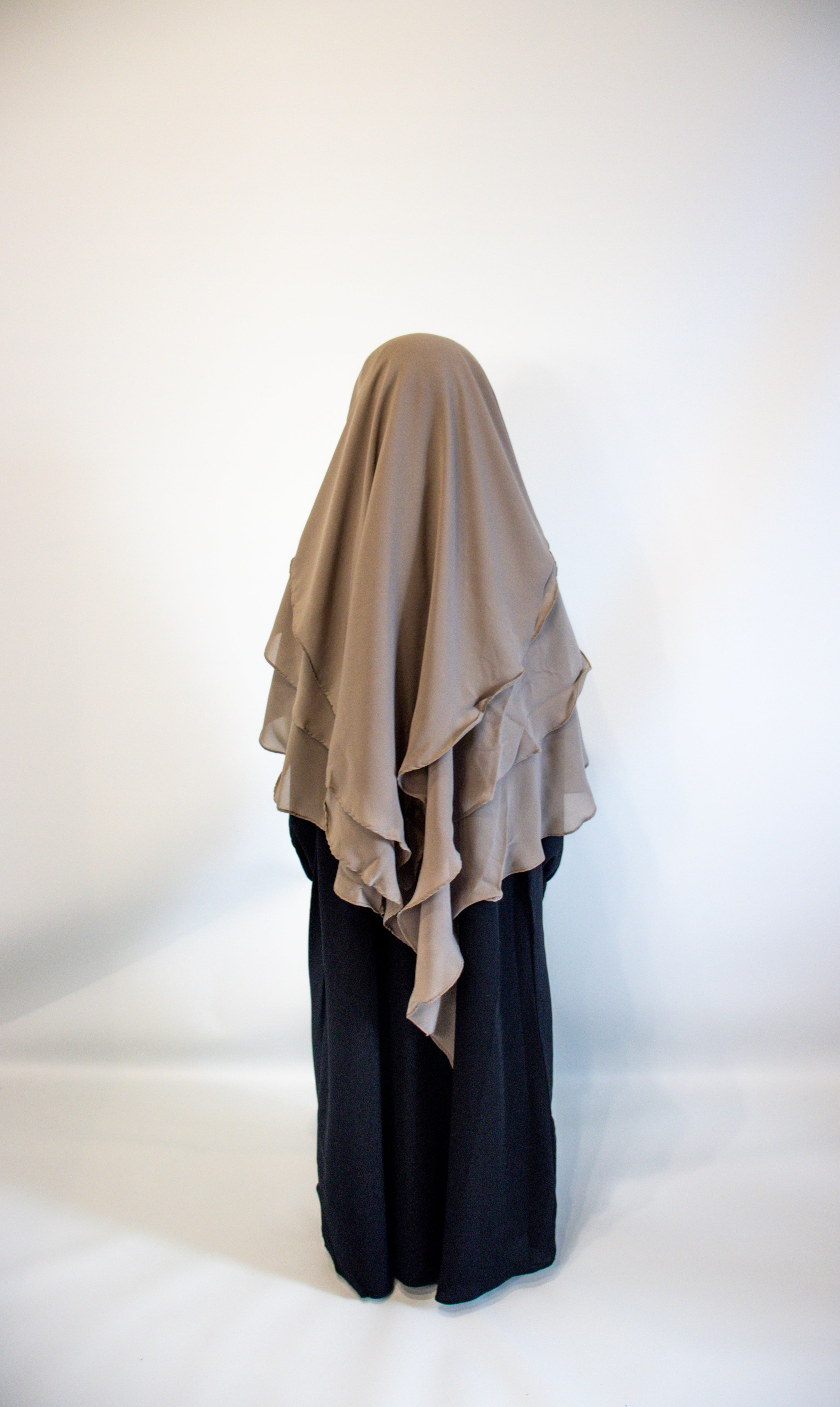 Girl wearing a Taupe grey hijab and black outfit on a white background