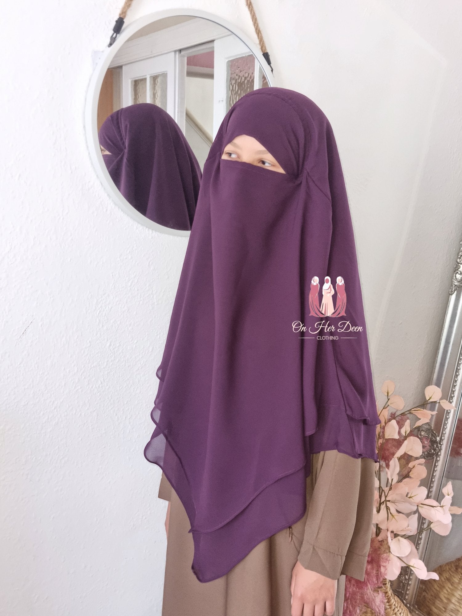 Girl in a 2 Layered Khimar  Headscarf with against a mirror on a wall background 
